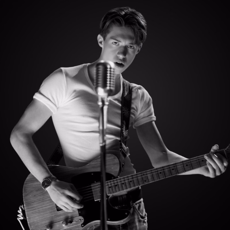 Odin Sokač performing, singing into a vintage microphone with an electric guitar